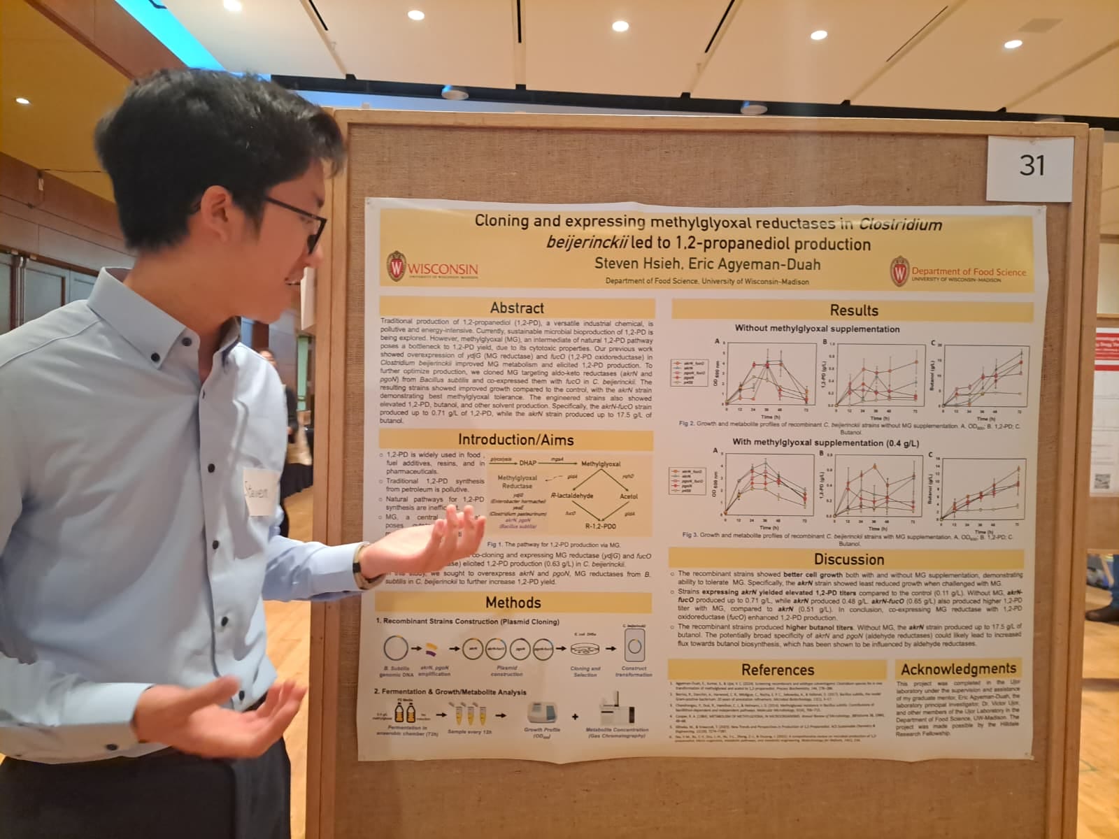 Man in blue button down shirt, presenting his research on a poster.