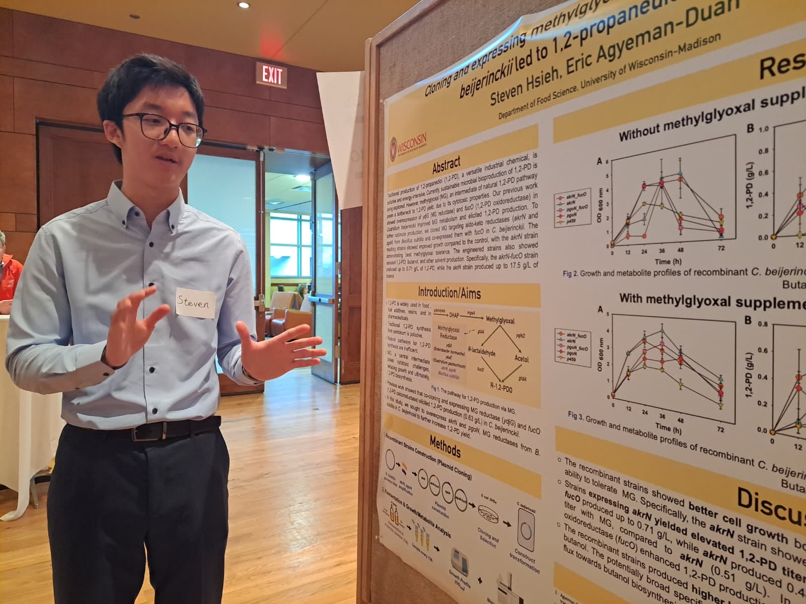 Man in blue button down shirt, presenting his research on a poster.